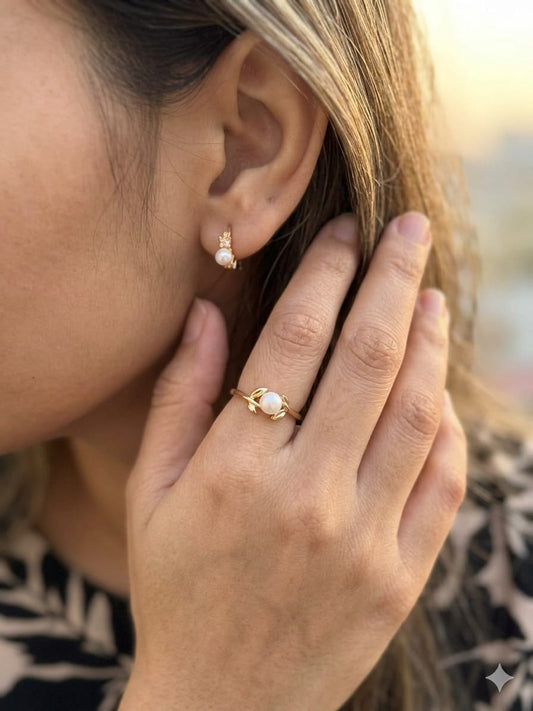 These dainty gold huggie earrings feature a delicate leaf design and a central pearl accent